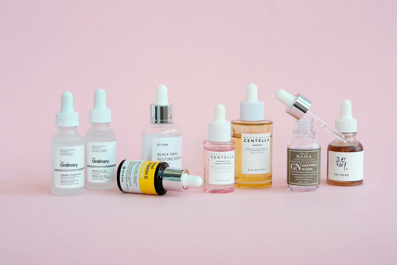 Korean skincare products arranged on a pink background, illustrating an Anua skincare review