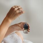 Hand holding a black glass serum bottle, illustrating a skincare serum review