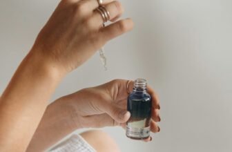 Hand holding a black glass serum bottle, illustrating a skincare serum review